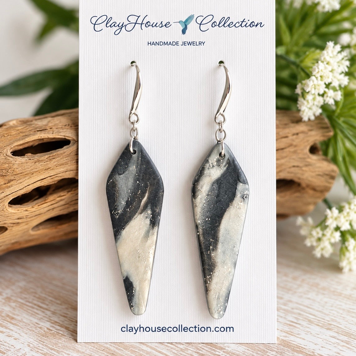 Handmade iridescent white polymer clay heart dangle earrings with opal-inspired shimmer and polished gold-tone ball studs displayed on a ClayHouse Collection jewelry card.