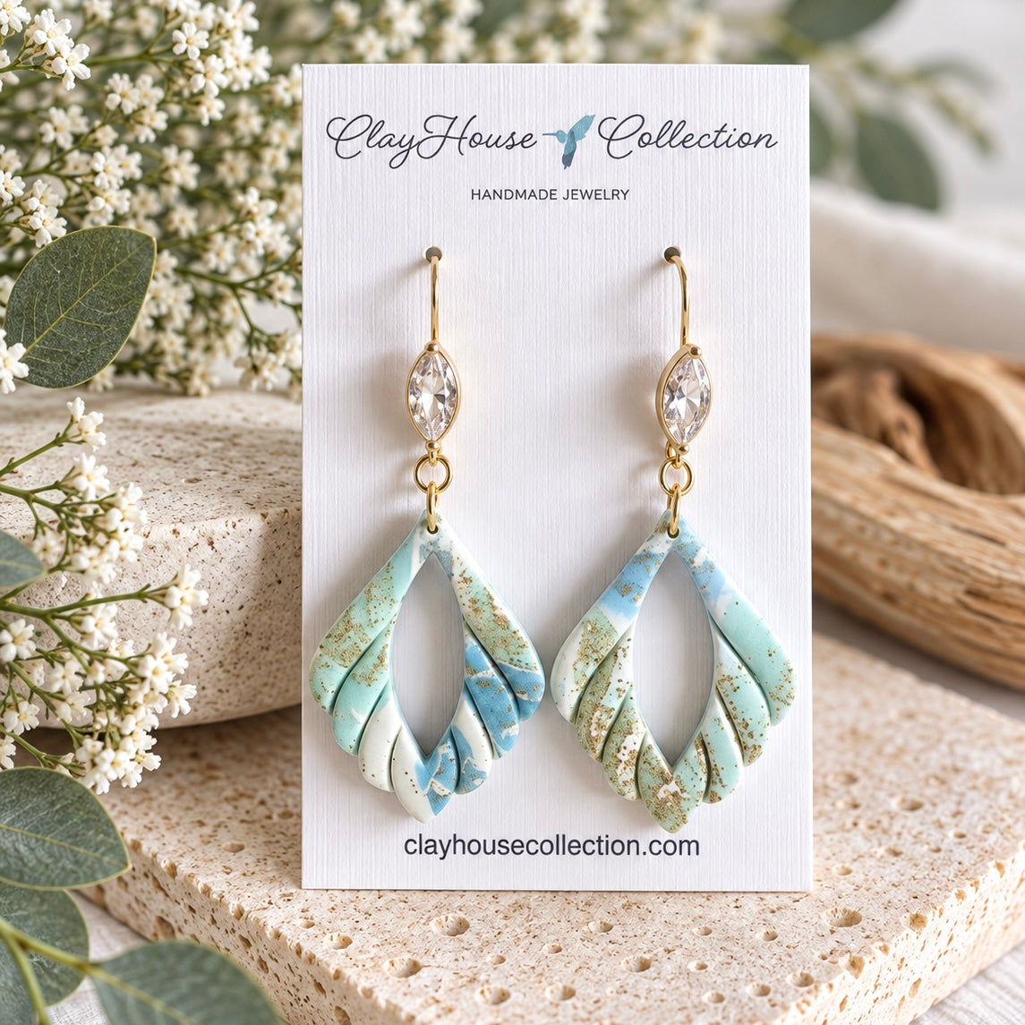 Aqua, blue and ivory open teardrop polymer clay dangle earrings with gold flecks and clear marquise crystal accents on a ClayHouse Collection card.