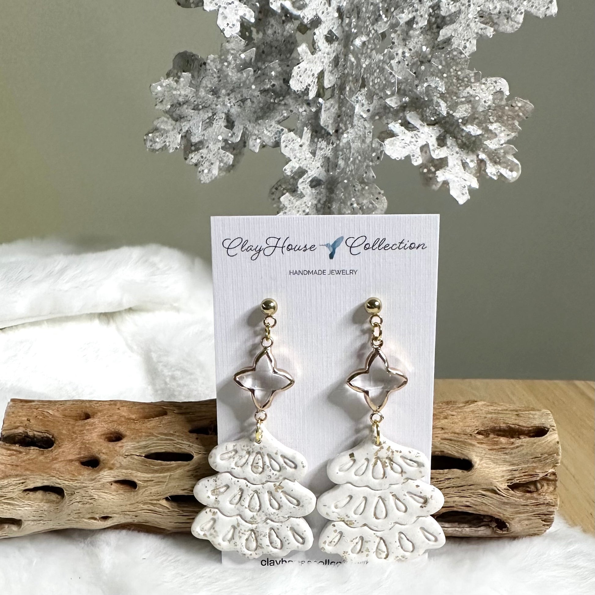 White lace-style earrings on a 'Clay House Collection' card with driftwood and coral in the background.