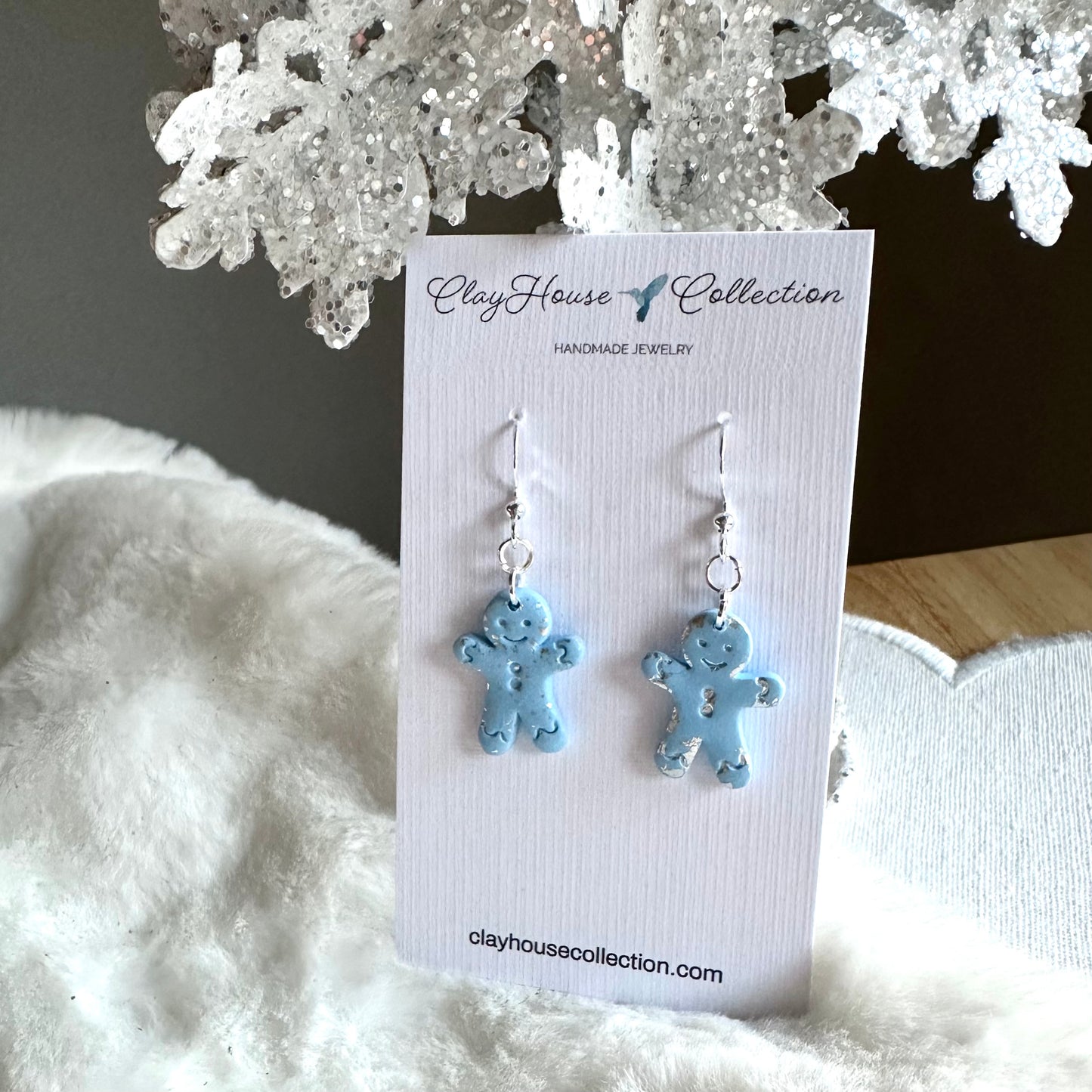 Blue teddy bear earrings on a Clay House Collection card with decorative background