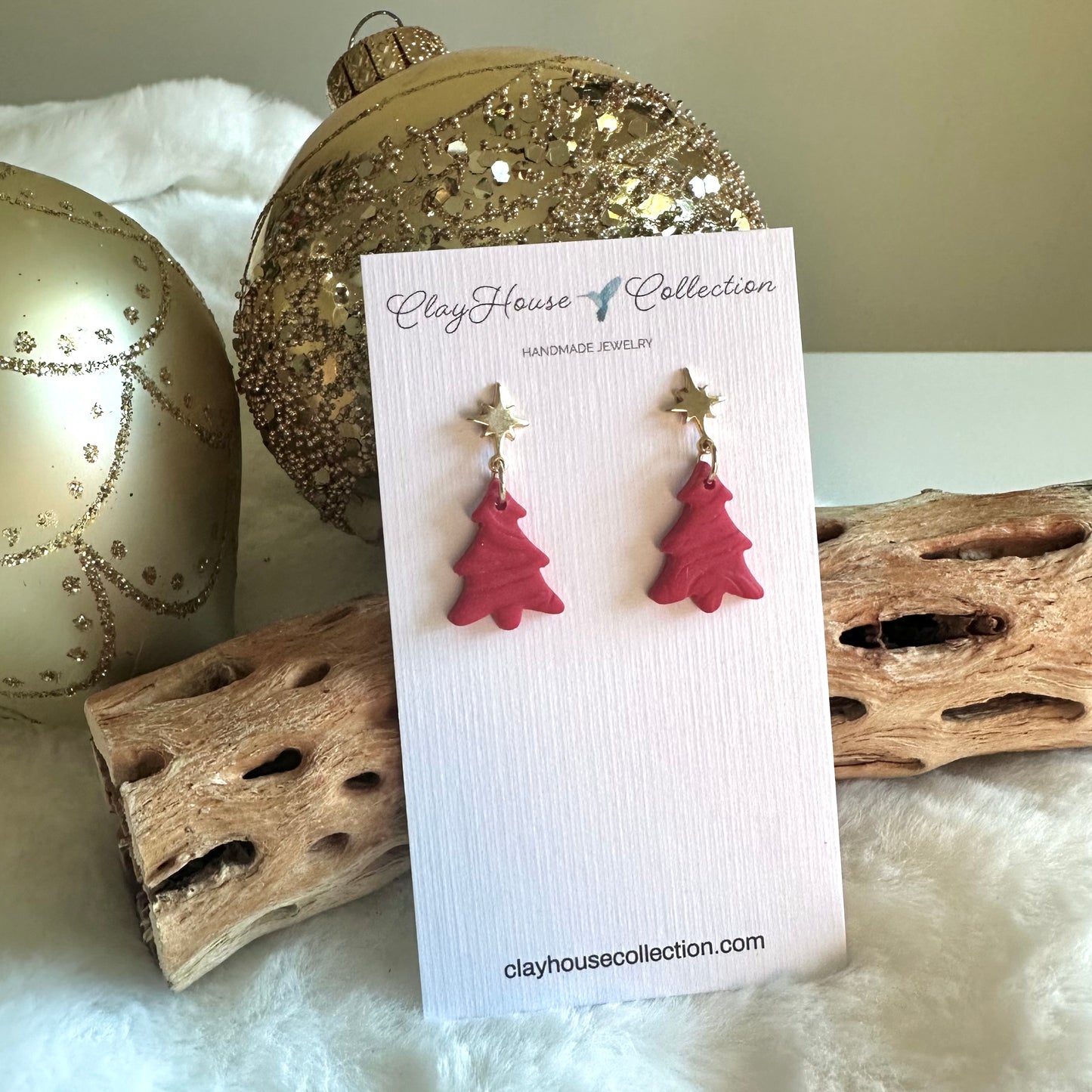 Red Christmas tree earrings on a Clay House Collection card with decorative background