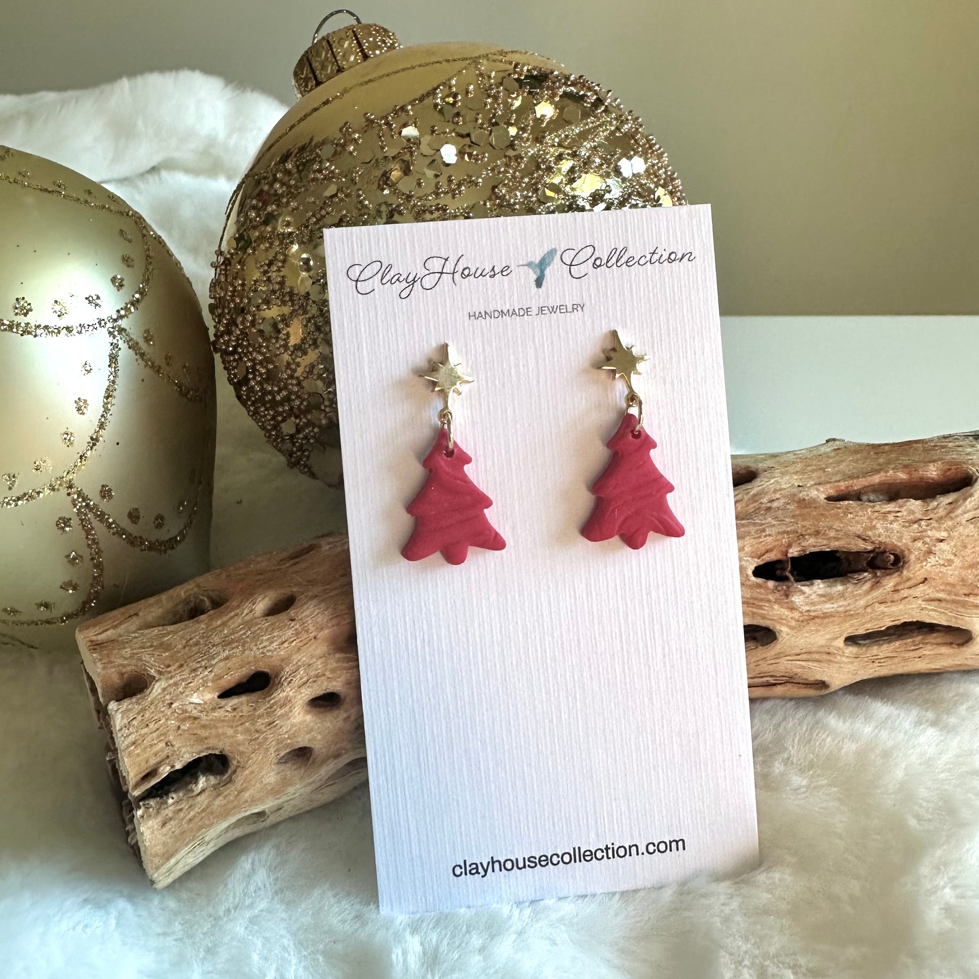 Red Christmas tree earrings on a Clay House Collection card with decorative background