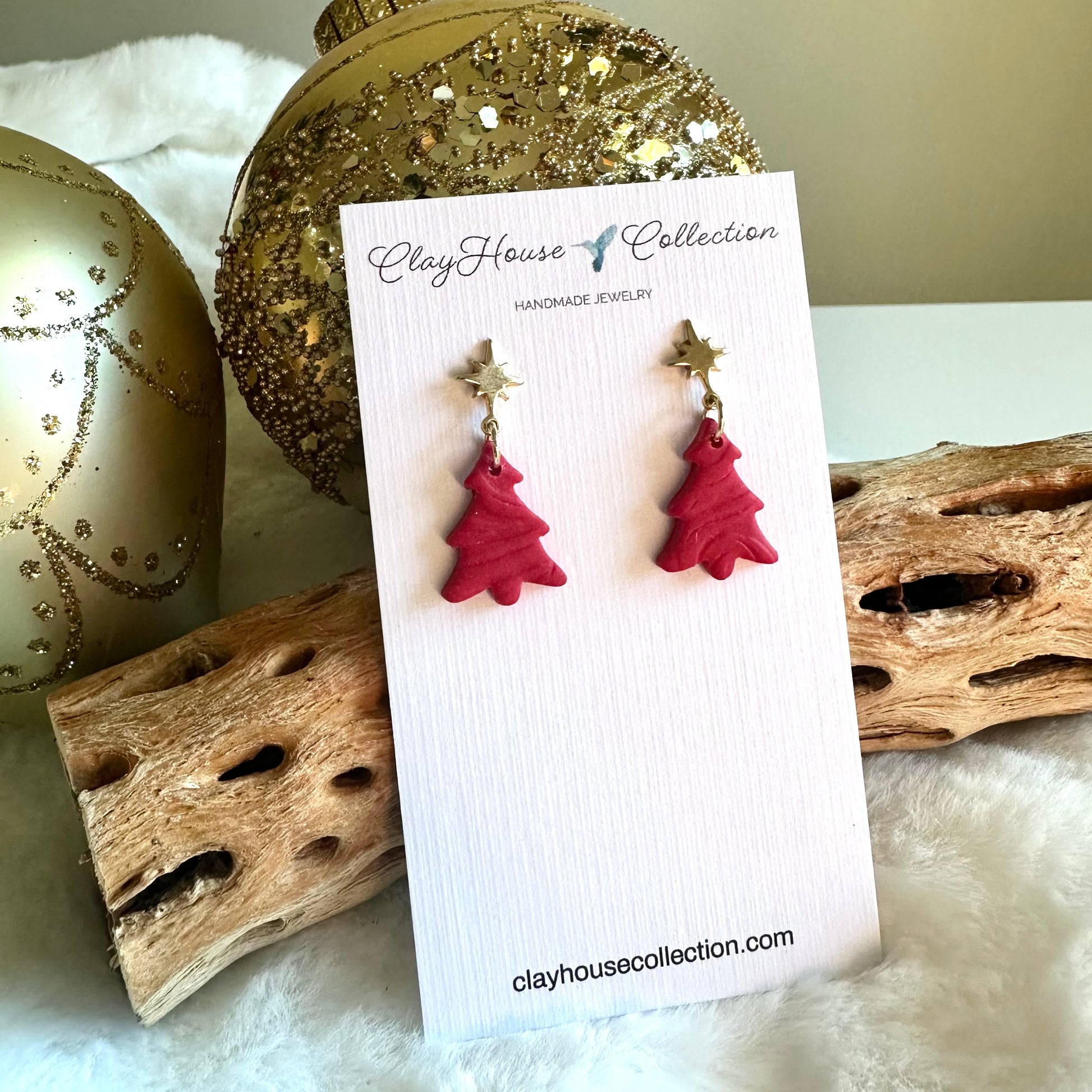 Red Christmas tree earrings on a Clay House Collection card with decorative background