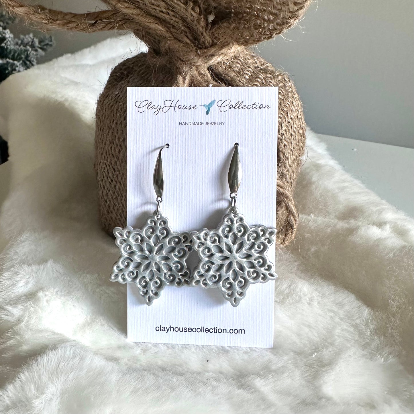 Snowflake earrings on a ClayHouse Collection card with a textured background