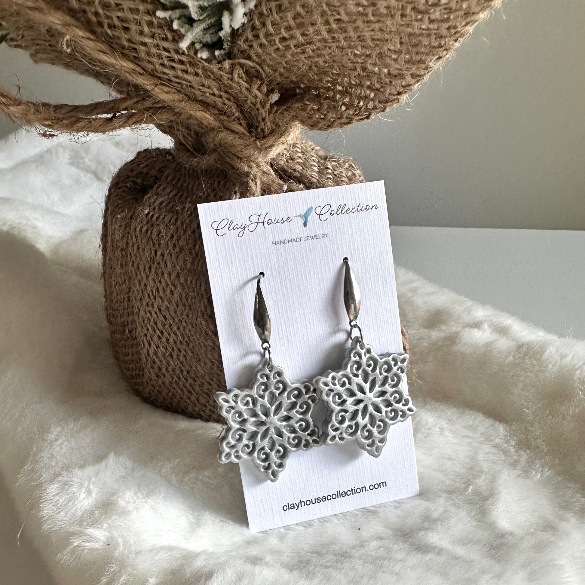Silver floral earrings on a Clayhouse Collection card with a textured background