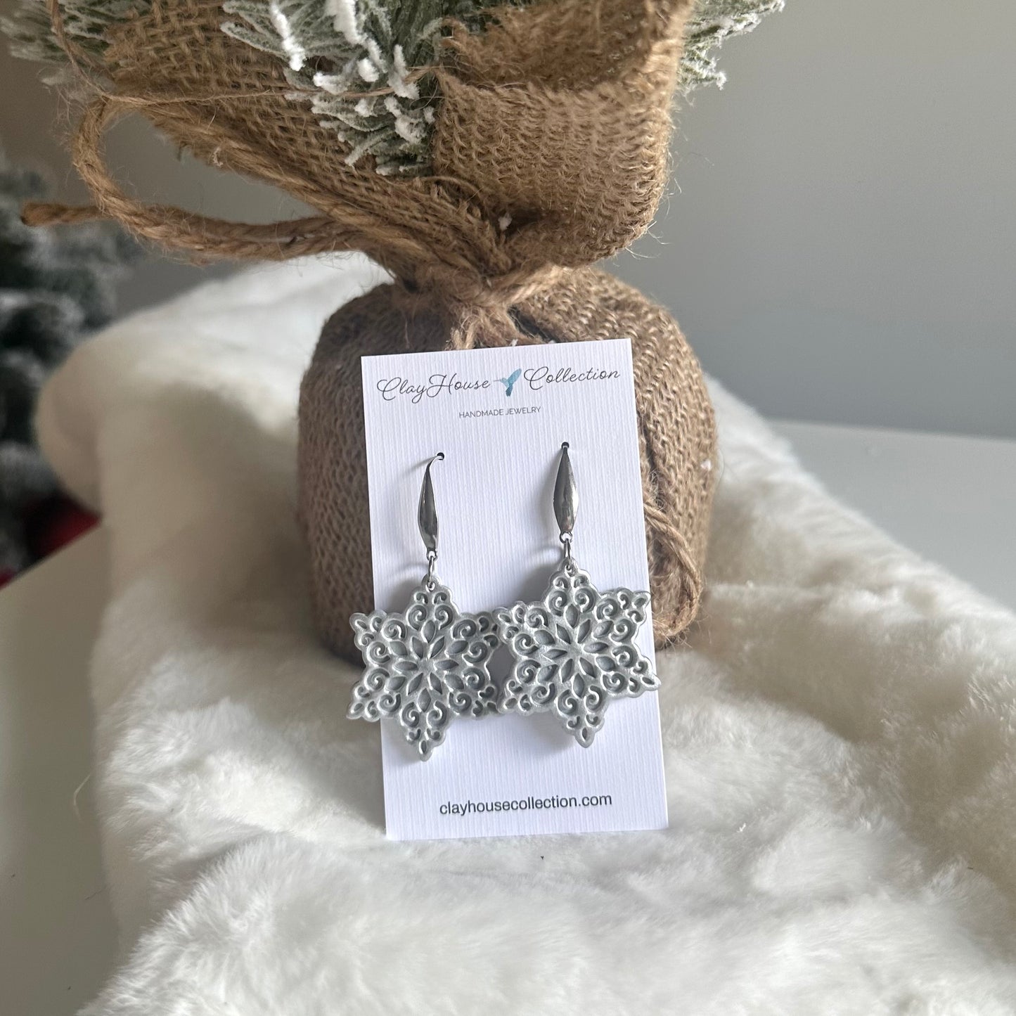 Silver snowflake earrings on a Clayhouse Collection card with a textured background